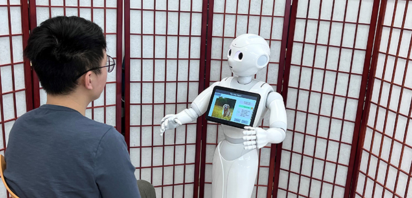 student seated interacting with white robot