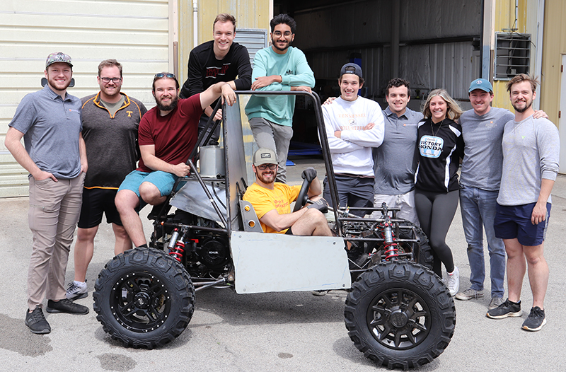 students standing in from of baja vehicle they built