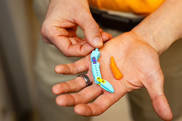 Dustin Crouch holds the thumb prosthetics in his hand.